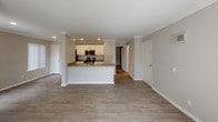 Located at 4306 Cassanna Way in Oceanside, California, this single-story home offers a well-designed open-concept layout with a clean, contemporary aesthetic. The living area is bright and spacious, featuring light wood-style flooring, neutral gray walls, crown molding, and multiple windows with vertical blinds that allow generous natural light to fill the space. A wall-mounted AC unit provides climate control, and a sliding glass door connects the interior to an outdoor area.

The kitchen is thoughtfully designed with white shaker-style cabinetry, warm beige countertops, and a suite of stainless steel appliances including a refrigerator, range, and over-the-range microwave. A peninsula with a sink separates the kitchen from the main living space, making it ideal for both cooking and entertaining.

The bedroom features plush carpeting, a ceiling fan with light fixture, and a sliding glass door that opens to a private outdoor patio, adding both function and natural light.

The bathroom is finished with white cabinetry, brushed nickel hardware, a wide vanity mirror, warm countertops, wood-look flooring, and a grab bar for added accessibility. Recessed lighting and a multi-bulb vanity fixture provide ample illumination. Overall, the home presents a cohesive, move-in-ready environment with modern updates throughout.