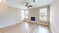 Located in D'Iberville, Mississippi, this single-story 2-bedroom, 2-bathroom home offers a thoughtfully designed layout with a comfortable, modern aesthetic. The open-concept living area features light hardwood-style flooring, crown molding, and a ceiling fan, with natural light streaming through multiple windows fitted with blinds. A built-in electric fireplace serves as a focal point, adding warmth and ambiance to the space. The kitchen is efficiently designed with white shaker-style cabinetry, stainless steel appliances including a refrigerator, microwave, and range, and a white countertop peninsula illuminated by sleek pendant lighting — seamlessly connecting to the living area. Both bedrooms are carpeted and equipped with ceiling fans, offering a cozy retreat. The spacious primary bedroom includes its own closet and is generously sized. Each bathroom features a tub-shower combination with brushed nickel fixtures, a white vanity, and wood-style flooring. A hallway connects the main living spaces, while two dedicated closets provide ample storage. The attached garage offers convenient enclosed parking with an automatic opener. The neutral color palette and clean finishes throughout create a bright, move-in-ready environment.