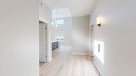 Located at 50 Main St in the heart of Hackensack, NJ, this thoughtfully designed single-floor residence combines contemporary finishes with an open, airy layout. The main living area immediately impresses with dramatically soaring ceilings, a skylight, and an abundance of natural light streaming through large windows that frame views of the surrounding Hackensack cityscape, including a notable historic courthouse. Light-toned hardwood flooring flows throughout the main living spaces, enhancing the sense of openness and warmth.

The kitchen is a standout feature, boasting rich dark-stained cabinetry that extends to ceiling height, stainless steel appliances including a range, microwave, and French door refrigerator, a herringbone tile backsplash, open shelving, and a generous central island topped with elegant marble-look quartz countertops and pendant lighting above.

The bedrooms offer plush neutral carpeting, ceiling fans, and large windows that invite natural light and exterior views. The bathroom is well-appointed with a dark wood vanity, white quartz countertop, full soaking tub, and floor-to-ceiling tile surround. A dedicated in-unit laundry area with a stacked washer and dryer adds everyday convenience. Stylish brass wall sconces and modern fixtures complete the refined aesthetic throughout.