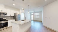 Located at 11750 Alliance Cir in Chester, VA, this well-appointed 3-bedroom, 2-bathroom single-floor residence offers a thoughtfully designed layout with contemporary finishes throughout. The open-concept kitchen and living area serves as the heart of the home, anchored by a large granite-topped island with an undermount sink and elegant pendant lighting. White shaker cabinetry, a grey tile backsplash, and a full suite of stainless steel appliances — including a refrigerator, range, and microwave — give the kitchen a clean, modern aesthetic. The living area extends naturally from the kitchen, bathed in natural light from oversized windows and a glass door that opens to a private balcony. A ceiling fan adds comfort to the bright, airy space. Light wood-style flooring flows throughout the main living areas, while the bedrooms feature plush carpet for added warmth. The spacious primary bedroom includes a dedicated closet and an en-suite bathroom with granite vanity counters, white cabinetry, and wood-look flooring. The second bathroom features a soaking tub with tiled surround and brushed nickel fixtures. Additional closets provide generous storage throughout. The overall ambiance is bright, clean, and move-in ready, reflecting a modern residential design sensibility.