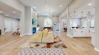 Located at 8801 Citrus Village Dr in Tampa, FL, this single-story community space offers a well-appointed, open-concept floor plan finished in light, neutral tones throughout. Light wood-style flooring flows seamlessly across the entire space, enhancing its bright and welcoming ambiance.

The expansive kitchen is a standout feature, boasting white shaker cabinetry with matte black hardware, dual white quartz countertop islands, a farmhouse-style sink, and elegant pendant lighting. A coffee and beverage station adds a functional, hospitality-oriented touch.

The adjoining living room is generously proportioned with soaring ceilings, recessed lighting, and a striking arched floor-to-ceiling window that fills the space with natural light and frames lush outdoor greenery. A decorative fireplace with patterned tile surround, a wall-mounted TV, and a chandelier complete the area, which also accommodates a game table for recreational use.

Two dining areas offer flexible gathering options. One features a large rectangular wooden table with modern white chairs and a wall-mounted TV, ideal for presentations or group dining. The other provides a casual round-table setting with upholstered seating. A welcoming foyer with architectural columns and stylish décor completes this versatile, community-focused space.