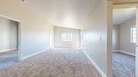 This single-story residence presents a clean, neutral aesthetic throughout its well-organized layout. The galley-style kitchen is a functional highlight, featuring white cabinetry, granite countertops, a subway tile backsplash, a stainless steel gas range, built-in microwave, dishwasher, and wood-look plank flooring that lends warmth to the space.

The living area is generously proportioned, with plush carpeting, elevated ceilings, and a front entry door that anchors the room. Natural light filters in through a side window, brightening the open feel of the space.

Multiple bedrooms are present, each finished with soft carpeting and windows that frame outdoor views. Vaulted ceilings in the primary bedroom add a sense of volume, while a wide closet with a hanging rod provides practical storage. Additional bedrooms include standard closets and natural light from exterior-facing windows.

Two full bathrooms serve the unit, both featuring white vanities with granite countertops, tub-shower combinations with tiled surrounds, and warm wood-look plank flooring. A multi-bulb vanity light fixture in one bathroom enhances visibility. Overall, the space maintains a bright, move-in-ready atmosphere with consistent finishes throughout.