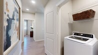 This thoughtfully designed single-floor residence offers a seamless open-concept layout connecting the living, dining, and kitchen areas. The kitchen is a functional centerpiece, outfitted with dark espresso cabinetry, stainless steel appliances, a white subway tile backsplash, and a generous granite-topped island with bar seating — ideal for both everyday cooking and entertaining. The adjacent dining area comfortably accommodates a full table and is bathed in natural light from large windows dressed with plantation shutters and linen drapes. The living room continues the bright, airy feel with light wood-style flooring throughout, a ceiling fan, and a large window framing outdoor views. Multiple bedrooms provide comfortable retreats; the primary bedroom features a ceiling fan, ample natural light, and access to a private en-suite bathroom complete with a granite vanity, dark wood cabinetry, and a walk-in closet with wire shelving. A second full bathroom mirrors the refined finishes, offering a tub/shower combination with tile surround. Additional bedrooms are well-proportioned with natural light and closet storage. A dedicated in-unit laundry area adds everyday convenience. Neutral warm-toned walls and consistent light wood flooring unify the space throughout.