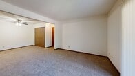Located at 1000 S Basswood Cir in Bloomington, Indiana, this one-bedroom, one-bathroom unit offers a practical and comfortable single-floor layout. The kitchen features warm wood cabinetry extending to the ceiling, a light-colored countertop with a built-in sink, and includes essential appliances such as a refrigerator and stove. A ceiling fan overhead and an open pass-through design give the kitchen an accessible, efficient feel. The living area is carpeted in a neutral tone, providing a comfortable foundation throughout the main spaces, and is connected via hallways that contribute to a straightforward and functional flow. The bedroom is a well-proportioned, private retreat with soft carpet flooring, a window with blinds that allows natural light and outdoor views, and a double sliding-door closet offering ample storage. An additional closet is accessible from the hallway near the bedroom, adding further storage convenience. The bathroom is clean and utilitarian, featuring a full-size tub and shower combination with a curtain rod, a toilet, and neutral white finishes throughout. White walls and wood-toned trim accents are consistent throughout the unit, creating a cohesive and understated aesthetic suited for comfortable everyday living.