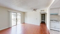 Located in the heart of Los Angeles' Koreatown neighborhood, this one-bedroom, one-bathroom unit at 843 Irolo St offers a practical and well-organized layout. Warm hardwood-style flooring flows throughout the living areas and bedroom, creating a cohesive and inviting aesthetic. The living room is the heart of the unit, featuring a ceiling fan, textured ceiling, and a sliding glass door that opens to a private balcony — allowing natural light to fill the space and providing views of the surrounding neighborhood. Vertical blinds offer privacy and light control. The kitchen is outfitted with clean white cabinetry, gray countertops, a double stainless steel sink with a modern pull-down faucet, and a window that brings in additional natural light — ideal for everyday cooking. The bedroom is a comfortable retreat with its own ceiling fan, a closet, and a sliding glass door that also connects to the balcony. The bathroom includes a tiled shower-tub combo with sliding glass doors, a toilet, and a vanity. A hallway and closet round out the layout, providing practical storage. The unit's neutral color palette and consistent flooring give it a clean, move-in-ready feel throughout.