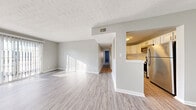 This single-floor residence offers a thoughtfully designed layout that balances open communal spaces with private retreats. The living area is bright and welcoming, featuring light-toned wood-look flooring, neutral gray walls, and a large sliding glass door fitted with vertical blinds that invites an abundance of natural light. A textured ceiling adds character throughout the common areas.

The kitchen is well-equipped and modern, showcasing white shaker-style cabinetry, white quartz countertops, and a classic white subway tile backsplash. Stainless steel appliances — including a range, dishwasher, and microwave — provide a clean, contemporary finish. A peninsula-style counter connects the kitchen to the main living area, enhancing the open flow of the space. A ceiling fan in the adjoining dining area adds both function and comfort.

A hallway leads to the private bedroom spaces, each finished with plush wall-to-wall carpeting and neutral tones that create a calm, restful atmosphere. Windows with blinds allow for natural light while maintaining privacy.

The bathrooms are clean and refined. One features a tub-shower combination adorned with striking marble-patterned tile surround, paired with a white vanity and wood-look flooring. A second bathroom provides a compact, functional layout with coordinating finishes throughout. The consistent use of light tones and modern fixtures gives the entire space a cohesive, updated feel.