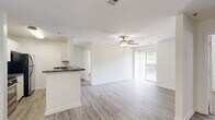 Located at 111 N Marietta Pkwy NE in Marietta, Georgia, this 2-bedroom, 2-bathroom residence offers a well-organized, single-level layout designed for comfortable everyday living. The open-concept living and kitchen area serves as the heart of the home, featuring light gray hardwood-style flooring that extends throughout the main living space. The kitchen is anchored by white cabinetry, dark granite-style countertops, a breakfast bar peninsula, and a pendant chandelier overhead. The living area flows naturally toward a sliding glass door that opens onto a private balcony, bringing in natural light and outdoor views. A ceiling fan with a light fixture keeps the space comfortable year-round. Both bedrooms are carpeted and generously proportioned, each equipped with a ceiling fan and a dedicated walk-in or reach-in closet for ample storage. Natural light filters in through windows dressed with blinds or vertical shades. The two full bathrooms each include a full-size tub and shower combination with clean white surrounds and chrome fixtures. One bathroom features wood-style flooring and dark countertops, while the other maintains a bright, all-white aesthetic. The overall design is clean, neutral, and move-in ready, offering a practical and comfortable living environment.