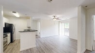 Located at 111 N Marietta Pkwy NE in Marietta, Georgia, this 2-bedroom, 2-bathroom residence offers a well-organized, single-level layout designed for comfortable everyday living. The open-concept living and kitchen area serves as the heart of the home, featuring light gray hardwood-style flooring that extends throughout the main living space. The kitchen is anchored by white cabinetry, dark granite-style countertops, a breakfast bar peninsula, and a pendant chandelier overhead. The living area flows naturally toward a sliding glass door that opens onto a private balcony, bringing in natural light and outdoor views. A ceiling fan with a light fixture keeps the space comfortable year-round. Both bedrooms are carpeted and generously proportioned, each equipped with a ceiling fan and a dedicated walk-in or reach-in closet for ample storage. Natural light filters in through windows dressed with blinds or vertical shades. The two full bathrooms each include a full-size tub and shower combination with clean white surrounds and chrome fixtures. One bathroom features wood-style flooring and dark countertops, while the other maintains a bright, all-white aesthetic. The overall design is clean, neutral, and move-in ready, offering a practical and comfortable living environment.