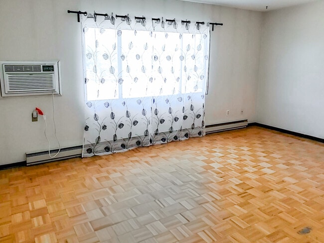 Enjoy a bright and airy living space at 1025 Munroe Apartments, featuring large windows that let in plenty of natural light. - Munroe Manor