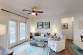 This thoughtfully designed single-floor residence offers a seamless open-concept layout that connects the kitchen, dining, and living areas into one cohesive living space. The kitchen is a standout feature, boasting dark espresso cabinetry that reaches to the ceiling, granite countertops, a subway tile backsplash, and a full suite of stainless steel appliances including a refrigerator, range, and over-the-range microwave. A central island with matching granite provides additional prep space and casual seating, accented by elegant pendant lighting overhead. Rich hardwood-style flooring flows throughout the main living areas, adding warmth and continuity. The living room is bright and welcoming, with large windows fitted with blinds, a ceiling fan, and direct access to natural light. A dedicated dining nook, illuminated by track lighting, offers an intimate space for meals. The bedroom is carpeted and comfortable, featuring a ceiling fan, a well-sized window with outdoor views, and ample natural light. The bathroom is finished with granite countertops, dark wood vanity cabinetry, a large mirror, and a tiled shower-tub combination. A dedicated in-unit laundry area with full-size side-by-side washer and dryer adds everyday convenience, completing this well-appointed residence.