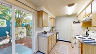 This single-floor, 3-bedroom, 1-bathroom home offers a compact and efficiently organized layout designed for comfortable everyday living. The open living area features soft carpeting, neutral wall tones, a textured ceiling, and a large window that fills the space with natural light. A ceiling fan adds practicality to the combined living and dining area, which flows directly into the kitchen. The kitchen is well-equipped with light wood cabinetry, gray laminate countertops, a built-in dishwasher, and a full-size refrigerator. A sliding glass door leads directly to an outdoor patio area, bringing in additional natural light and providing convenient outdoor access. The generously sized primary bedroom includes a sliding-door closet and a direct connection to the shared bathroom. The two additional bedrooms are carpeted and each feature sliding-door closets and individual heating units, offering flexibility for various uses. The full bathroom is finished with tile flooring, a wide vanity with ample counter space, a large mirror, and a shower-tub combination. Throughout the home, warm wood-toned door and trim accents provide a cohesive, understated aesthetic.