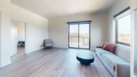 Located at 126 Langdon Street in Madison, Wisconsin, this modern apartment offers 820 square feet of thoughtfully designed single-floor living across 2 bedrooms and 2 bathrooms. The open living area features light hardwood-style flooring, neutral walls, and a sliding glass door that opens to a private balcony with sweeping views of the Madison skyline. The kitchen is well-appointed with stainless steel appliances including a refrigerator, range, microwave, and dishwasher, complemented by gray shaker-style cabinetry, white subway tile backsplash, quartz countertops, and distinctive reclaimed wood open shelving. A pendant light and breakfast bar add functional style to the space. The primary bedroom spans 140 square feet and features large windows with lake views, while the second bedroom offers city views and a double closet. Both bathrooms are finished consistently with wood-look flooring, gray vanities with white countertops, and full tub-shower combinations with chrome fixtures. Throughout the apartment, clean lines and a neutral color palette create a cohesive, contemporary aesthetic well-suited to urban living in downtown Madison.