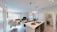 Located at 12810 Cypress Cape Cir in Fort Myers, FL, this well-appointed 2-bedroom, 2-bathroom single-story residence offers a thoughtfully designed layout with contemporary finishes throughout. The open-concept kitchen is a standout feature, showcasing dark espresso cabinetry, a subway tile backsplash, stainless steel appliances, and a large white quartz island with bar seating illuminated by stylish pendant lighting — ideal for both cooking and casual entertaining. Light wood-style flooring flows seamlessly through the main living areas, lending a clean, modern aesthetic. The dedicated dining room accommodates a full-sized table and is highlighted by a chandelier overhead and windows that invite natural light. The living room is bright and comfortable, featuring large windows with blinds that frame views of the surrounding greenery. The primary bedroom offers a generous footprint with plush carpeting, while the second bedroom is well-sized with a ceiling fan and ample natural light, making it equally suitable as a home office. Both bathrooms are finished with dark wood vanities, white quartz countertops, and tile shower surrounds with chrome fixtures. A dedicated laundry room with a full-sized washer and dryer adds everyday convenience, and two closets provide excellent storage throughout.