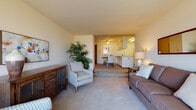 Located at 238 Randolph Dr in Madison, Wisconsin, this single-floor residence offers a well-organized layout with a warm, comfortable ambiance throughout. The living room is generously sized, featuring soft carpeting, a large sliding glass door that invites natural light and frames peaceful wooded views beyond. The space is versatile, accommodating both a main seating area and a secondary sitting nook, making it ideal for relaxing or entertaining. A few steps lead up to the dining and kitchen area, which is defined by a peninsula breakfast bar that provides casual seating and a natural divider between the two spaces. The kitchen is equipped with white cabinetry, built-in appliances including a microwave and range, and a ceiling fan overhead that adds to the room's functionality. The bedroom is a quiet retreat, complete with plush carpeting, a sizable window overlooking a natural wooded backdrop, and ample closet storage. The full bathroom features white raised-panel cabinetry, a wide vanity with a large mirror, and a tub-shower combination with tile flooring. Throughout the home, neutral tones and consistent soft carpeting create a cohesive, understated aesthetic well-suited to comfortable everyday living in the Madison area.