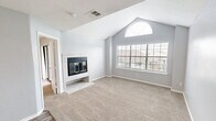 Located at 110 Lake Rd in Lake Jackson, TX, this one-bedroom, two-bathroom residence offers a well-designed single-floor layout with a variety of notable architectural features. The living room makes a striking impression with its vaulted ceilings and a tile-surround fireplace, creating a warm and inviting focal point. Large windows with blinds allow natural light to fill the space, and views of the well-maintained, landscaped community grounds can be enjoyed from the private balcony. The kitchen and living area flow seamlessly together, with the kitchen featuring a peninsula breakfast bar topped with granite-style counters, white cabinetry, a white subway tile backsplash, and black appliances including a range, over-the-range microwave, and refrigerator. Wood-look flooring runs throughout the main areas, while plush carpet adds comfort to the bedroom. The spacious bedroom includes a ceiling fan, a mirrored sliding-door closet, and vaulted ceilings accented by an arched window that brings in abundant natural light. Two full bathrooms feature granite-style vanity tops, white cabinetry, and tub/shower combinations. A dedicated closet provides additional storage, completing this thoughtfully designed residence.