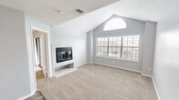 Located at 110 Lake Road in Lake Jackson, TX, this one-bedroom, one-bathroom unit offers a well-designed layout across a single floor. The living and dining area is an immediate standout, featuring dramatic vaulted ceilings that rise to a striking arched window, flooding the room with natural light. A tile-surround fireplace with glass doors serves as the focal point of the space, adding warmth and character. Soft carpeting and neutral gray walls create a clean, cohesive aesthetic throughout. The kitchen is thoughtfully designed with white cabinetry, subway tile backsplash, granite-style countertops, and a breakfast bar peninsula that opens to the dining and living areas. Black appliances, including a range, microwave, and refrigerator, complement the crisp white finishes, while wood-look flooring ties the space together. The bedroom offers comfortable proportions, carpet flooring, a ceiling fan, and a mirrored sliding-door closet providing ample storage. The bathroom includes a full tub-shower combo, granite-style vanity countertop, and white cabinetry. A dedicated laundry area and a hallway add to the unit's functionality. The private balcony overlooks well-maintained green grounds, offering a pleasant outdoor retreat with views of the landscaped community.