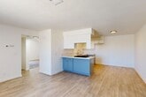 Located at 800 S Norma St in Ridgecrest, California, this single-floor 2-bedroom, 1-bathroom home offers a thoughtfully designed layout with clean, modern finishes throughout. The open-concept living, dining, and kitchen area serves as the heart of the home, featuring light wood-look flooring that extends seamlessly across the space. The kitchen stands out with a distinctive two-tone design — bold blue lower cabinetry paired with crisp white upper cabinets — along with a built-in sink, gas cooktop, and ample counter space. A secondary kitchen area provides additional grey shaker-style cabinetry, a sink, and a dishwasher. The living area is bright and airy, with a large window fitted with vertical blinds allowing generous natural light. Both bedrooms are carpeted and equipped with ceiling fans, offering a comfortable and cozy feel. The primary bedroom includes a door with a window panel that brings in additional natural light. The full bathroom is well-appointed with wood-look flooring, a dual-sink vanity, a shower-tub combo, and accessibility grab bars throughout. A hallway connects the main living areas to the bedrooms, completing this functional and inviting single-story home.