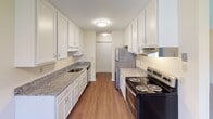 This single-floor residence offers a thoughtfully arranged layout that balances practicality and comfort throughout its main living spaces. The galley-style kitchen is a standout feature, showcasing white cabinetry extending to the ceiling, granite-look countertops, hardwood-style flooring, and stainless steel appliances including a refrigerator, electric range, and dishwasher — providing ample storage and workspace.

The living area is generously proportioned, featuring wall-to-wall carpeting and soft, neutral tones that create a welcoming atmosphere. A sliding glass door opens directly onto a private balcony, bringing in natural light and offering views of surrounding greenery. A wall-mounted air conditioning unit and baseboard heating ensure year-round comfort.

The bedroom is a quiet, comfortable space with plush carpeting, a window allowing natural light, and baseboard heating. An entryway with hardwood-style flooring leads into the unit, providing a clean transition between spaces and convenient closet access nearby.

The full bathroom is finished with tile flooring, a white vanity with marble-look countertops, white cabinetry for storage, and a tub-shower combination with white tile surround. Warm yellow-toned walls add a light, airy feel throughout the unit.