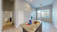 This contemporary 910 square foot apartment in Charlotte, NC offers a harmonious blend of style and functionality. The space boasts two bedrooms and two bathrooms, with the primary bedroom measuring a spacious 170 square feet. The open-concept design is immediately apparent, with high ceilings that create an airy atmosphere throughout.

The kitchen is a focal point, featuring dark wood cabinetry contrasted by light granite countertops. Stainless steel appliances, including a refrigerator and built-in microwave, add a modern touch. An island with a sink provides additional prep space and casual seating.

Both bathrooms showcase elegant finishes, with one featuring a double vanity with a granite countertop and large mirror. The shower areas are adorned with subway tiles, adding a classic yet contemporary feel.

The bedrooms are generously sized, with plush carpeting and large windows that allow ample natural light. Built-in closets offer practical storage solutions. Throughout the apartment, neutral wall colors create a calm ambiance and provide a blank canvas for personalization.

Light wood-look flooring in the main living areas adds warmth and ties the space together. The apartment's layout, as seen in the 3D floor plan, shows a well-thought-out design that maximizes space and flow. This residence at 2120 N. Brevard St. combines comfort and style in a compact yet inviting package.
