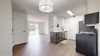 This efficient and thoughtfully designed 2-bedroom, 1-bathroom single-floor residence offers a clean, modern aesthetic throughout. The open-concept living and kitchen area serves as the heart of the home, featuring light wood-tone laminate flooring, crisp white walls, and a textured ceiling. The living room is bright and airy, highlighted by a large sliding glass door that frames outdoor greenery and fills the space with natural light.

The kitchen is well-appointed with white upper cabinetry, dark wood lower cabinets, light countertops, and a full suite of stainless steel appliances including a refrigerator, range, microwave, and dishwasher. A skylight above the kitchen adds additional brightness to the cooking area.

Both bedrooms are comfortably sized, with the primary bedroom featuring plush carpeting, a window with outdoor views, and access to a dedicated closet. The second bedroom continues the home's consistent, neutral palette with wood-tone flooring.

The bathroom is finished with a dark-toned vanity, framed mirror, and wood-look flooring, offering a clean and contemporary feel. Two closets provide practical storage throughout the unit. A connecting hallway ties all rooms together, creating a logical and functional floor plan. Overall, the space presents a modern, move-in-ready environment with consistent finishes and a bright, welcoming ambiance.