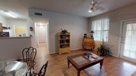 This thoughtfully designed 1-bedroom, 1-bathroom model unit offers a comfortable and functional single-floor layout. The living room serves as the heart of the home, featuring warm hardwood flooring, a ceiling fan with light fixture, and a welcoming ambiance enhanced by natural light streaming through large windows with vertical blinds and a glass-paned exterior door that opens to the outdoors. The space easily accommodates a seating area and dining arrangement, creating a versatile living environment.

The kitchen is efficiently laid out in an L-shape, outfitted with warm-toned oak cabinetry, light countertops, a double-basin sink, and white appliances including a range, dishwasher, and refrigerator. Light tile flooring adds a clean, practical touch to the space.

The bedroom is a comfortable retreat featuring plush carpet, a ceiling fan, a window with natural light, and access to a dedicated walk-in closet with built-in shelving — providing ample storage. The bathroom is well-appointed with tile flooring, a vanity with warm wood cabinetry, a large mirror with overhead lighting, and accessibility-friendly features including a grab bar near the toilet.

The entry foyer transitions smoothly from tile to hardwood and includes a conveniently located coat closet, completing this well-organized and inviting floor plan.