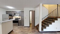 Located at 1812 16th St SE in Saint Cloud, Minnesota, this three-story home offers five bedrooms and two bathrooms across a well-distributed floor plan. The ground floor establishes the main living areas, including a combined kitchen and living room featuring a peninsula with granite-look countertops, dark cabinetry, stainless steel appliances, and durable wood-look flooring. A wall-mounted AC unit and natural light from street-facing windows add comfort to the living space. The two upper floors are nearly identical in size, each providing generous bedroom space. Several bedrooms are carpeted and feature open built-in closet systems with dedicated shelving, hanging rods, and shoe storage, offering practical organization. Natural light filters through horizontal-blind windows with views of mature surrounding greenery. The two bathrooms are finished with tile flooring; one features a full soaking tub and shower combination, while the other is a compact space tucked beneath a sloped ceiling. Textured ceilings are consistent throughout the home, and wood-tone baseboards frame each room. Hallways connect the floors efficiently via a central staircase, making the layout functional and easy to navigate. This home combines comfortable living spaces with ample storage in a multi-floor layout.