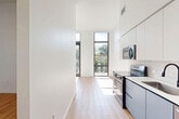 Located at 501 NW Seventh Terrace in Fort Lauderdale, FL, this modern 1-bedroom, 1-bathroom residence offers a thoughtfully designed single-floor layout with a clean, contemporary aesthetic throughout. The open-concept living area is anchored by soaring ceilings and floor-to-ceiling black-framed windows that flood the space with abundant natural light and frame views of the surrounding greenery. Light wood plank flooring runs seamlessly throughout, complementing the crisp white walls and minimalist design. The kitchen is outfitted with sleek white cabinetry, a subway tile backsplash, white quartz countertops, and stainless steel appliances including a range, microwave, and refrigerator, with a louvered pantry door adding a stylish touch. The living and dining area flows naturally toward a private balcony, accessible through full-height glass doors that invite in the Florida sunshine. The bedroom is a sun-drenched retreat with direct balcony access via large sliding glass doors. The bathroom features neutral large-format tile, a soaking tub with shower, a white vanity with quartz countertop, and matte black fixtures. Two closets, a dedicated laundry area, and a hallway with panel doors round out this well-appointed home.
