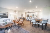Located at 303 Arrowhead Ln in South Setauket, NY, this well-appointed single-floor home offers a thoughtfully designed open-concept layout that seamlessly connects the living, dining, and kitchen areas. The living room features warm hardwood-style flooring, recessed lighting, and generous natural light, with a secondary sitting area positioned beside large windows framing lush outdoor views. The kitchen is a standout, showcasing white shaker cabinetry, a subway tile backsplash, stainless steel appliances, a gas range, and a spacious waterfall-edge island with pendant lighting — ideal for both cooking and casual dining. The dining area is defined by a bold navy accent wall adorned with woven décor, adding character to the open floor plan. Both bathrooms are finished with clean, modern aesthetics: the primary bath includes a dual-sink vanity with white cabinetry and geometric wallpaper, while the second bath offers a tiled tub-shower combo. The bedrooms are bright and comfortable, each with large windows overlooking the greenery outside. A dedicated in-unit laundry area with wire shelving provides added convenience. Throughout, the home maintains a cohesive, contemporary style with neutral tones and quality finishes.