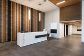 Melody's community amenity floor is a thoughtfully designed space that blends contemporary aesthetics with practical functionality. The entrance is anchored by a sleek, white reception desk boldly branded with the "MELODY" name in gold lettering, set against a dramatic floor-to-ceiling textured feature wall in rich, earthy tones. Polished concrete floors and wood-slat ceiling accents carry throughout, creating a cohesive modern industrial feel. Curated abstract artwork adorns the crisp white walls, adding an artistic touch to the welcoming corridor. The lounge area offers a comfortable retreat with a deep sofa, accent chairs in warm cognac leather, a wall-mounted flat-screen TV, and floor-to-ceiling windows that flood the space with natural light. A spacious social room serves as a hub for recreation and gatherings, featuring café-style seating, pendant lighting, a pool table, and expansive windows overlooking the surrounding neighborhood. The fully equipped community kitchen is outfitted with stainless steel appliances including a range with a professional hood, a side-by-side refrigerator, microwave, and ample counter space finished with a soft blue subway tile backsplash and warm wood cabinetry — ideal for entertaining and communal use.