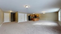 Located at 526 Middletown Rd in Hummelstown, PA, this single-floor space presents an open-concept layout that combines the living area and kitchen into one cohesive, expansive environment. The generous carpeted living area provides a comfortable and versatile space, bathed in natural light that highlights the neutral, warm-toned walls throughout.

The kitchen is well-appointed with warm wood cabinetry, dark countertops, and stainless steel appliances including a full-size refrigerator and built-in microwave. A kitchen island offers additional prep space and serves as a natural divider between the cooking and living areas. Pendant lighting above the island and a chandelier nearby add decorative touches that enhance the overall ambiance.

Two sets of double closet doors along one wall of the living area provide substantial built-in storage, a practical feature that adds to the unit's functionality. Flush-mount and pendant lighting fixtures are distributed throughout, ensuring the space is well-lit. The clean, simple aesthetic and open floor plan make this space highly adaptable to a variety of uses and furnishing arrangements.
