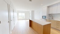 This thoughtfully designed two-bedroom, two-bathroom residence on Shakespeare Street in Pittsburgh's East End offers a clean, modern aesthetic throughout. Warm hardwood-style flooring flows seamlessly across the open-plan living areas, complementing the crisp white walls and contemporary finishes.

The kitchen is a standout feature, showcasing white upper cabinetry paired with natural wood-toned lower cabinets, a subway tile backsplash, stainless steel appliances, and a central island with a white countertop. A built-in entryway bench with storage and wall hooks adds practical charm near the entrance.

Both bedrooms are bright and well-proportioned, benefiting from large windows that frame elevated views of the Pittsburgh skyline and surrounding greenery. The primary bedroom connects conveniently to its own bathroom, while the second bedroom is equally light-filled with its own access to the second full bath.

The two bathrooms are finished with grey tile flooring, wood-toned vanities, illuminated mirrors, and white subway tile. One bathroom features a walk-in glass-enclosed shower, while the other includes a soaking tub. Two closets provide ample storage. This residence combines functional layout with modern design in a well-appointed Pittsburgh location.