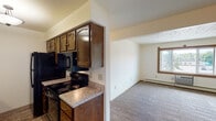 Located at 1532 W Ridge St in Marquette, Michigan, this single-floor unit offers a practical and well-organized layout suited for comfortable everyday living. The kitchen is outfitted with rich dark-stained wood cabinetry, light granite-style countertops, a double sink, and black appliances including an electric range, built-in microwave, dishwasher, and refrigerator. Tile flooring runs throughout the kitchen, providing a durable and easy-to-maintain surface. The living area is generously sized, featuring soft carpeting, a textured ceiling, baseboard heating, and a window with wood trim that allows natural light to fill the space. A wall-mounted air conditioning unit offers additional climate control. A hallway connects the main living space to the bedroom and bathroom. The bedroom is a well-proportioned room with plush carpeting, a ceiling fan with integrated lighting, a wood-trimmed window overlooking the outdoors, and baseboard heating. The bathroom includes a vanity with dark wood cabinetry and granite-style countertop, a tiled shower-tub combination, tile flooring, and clean neutral walls. Throughout the unit, warm wood accents on doors and window trim lend a cohesive, understated character to the overall design.