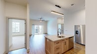 Located at 401 Haysland Rd SW in Huntsville, Alabama, this thoughtfully designed 2-bedroom, 2-bathroom residence offers a modern and functional layout across a single floor. The open-concept kitchen and living area serves as the heart of the home, showcasing wood-look flooring, high ceilings, and an abundance of natural light. The kitchen is equipped with stainless steel appliances, a tile backsplash, warm wood cabinetry, and a central island featuring a granite countertop and an integrated sink with a sleek matte black faucet — ideal for both cooking and casual dining. Linear pendant lighting above the island adds a contemporary touch. The living area flows seamlessly toward a sliding glass door that opens to a private balcony, extending the living space outdoors. Each bedroom is carpeted and includes a ceiling fan, with the primary bedroom featuring a stylish barn-style sliding door that leads to an en-suite bathroom with granite countertops and a tiled tub-shower combination. The second bedroom is bright and well-proportioned, with a window offering outdoor views. Both closets provide practical wire shelving for organized storage. The overall aesthetic is clean and contemporary, with neutral tones and modern black hardware accents throughout.