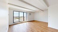 This 2-bedroom, 2-bathroom residence at 12000 Fairhill Rd in Cleveland, Ohio offers a well-designed single-floor layout with a clean, modern aesthetic. The open living room is a standout feature, showcasing large sliding glass doors that frame sweeping views of the Cleveland skyline and surrounding landscape, flooding the space with abundant natural light. Exposed ceiling beams add architectural character, while warm light wood flooring flows consistently throughout the entire unit.

The galley-style kitchen is thoughtfully appointed with white cabinetry, light countertops, a subway tile backsplash, stainless steel appliances including a full-size refrigerator and range, and a black matte faucet — offering both functionality and a contemporary feel.

The primary bedroom is generously sized with direct access to a private balcony through sliding glass doors, offering additional outdoor views. The secondary bedroom features crown molding, a built-in closet with a barn-style sliding door, and a sun-filled window with outdoor views.

Both bathrooms are updated with white vanities featuring gold and black hardware accents, framed mirrors, and walk-in shower stalls — one with a glass enclosure and one with a curtain rod setup — all finished with coordinating light wood flooring for a cohesive look.