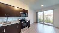 Located at 13081 SW 242nd St in Homestead, FL, this single-floor unit offers a clean, contemporary design throughout. The open-concept living and kitchen area is a standout feature, anchored by a well-appointed kitchen equipped with rich dark espresso cabinetry, granite countertops, stainless steel appliances including a range, over-the-range microwave, dishwasher, and refrigerator. Light wood-style flooring runs seamlessly across the main living areas, enhancing the bright and airy atmosphere.

The living area is bathed in natural light through large sliding glass doors that open to views of lush greenery and a well-maintained outdoor landscape, creating a seamless indoor-outdoor connection. Sheer vertical blinds provide privacy while maintaining the flow of natural light.

The bedrooms are bright and well-proportioned, with large windows framing views of the surrounding neighborhood and sky. The clean white walls and light flooring give each room a fresh, neutral palette. The bathroom features matching granite countertops, dark cabinetry, a single vanity with a large mirror, and light tile flooring, consistent with the modern aesthetic found throughout the unit. The overall design is cohesive, minimalist, and move-in ready.