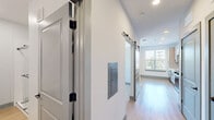 Located at 2500 Pelham Rd in Greenville, SC, this thoughtfully designed one-bedroom, one-bathroom unit offers a clean, modern aesthetic throughout. The open-concept kitchen and living area serves as the heart of the space, featuring light hardwood-style flooring, recessed lighting, and an abundance of natural light from large windows. The kitchen is well-appointed with shaker-style cabinetry in a soft gray-beige tone, white quartz countertops, a subway tile backsplash, a stainless steel undermount sink with a matte black faucet, and a full suite of stainless steel appliances including a refrigerator, range, built-in microwave, and dishwasher. A striking sliding barn door adds a contemporary architectural detail connecting the main living area to the hallway. The bedroom is carpeted for comfort and includes a ceiling fan, ample natural light from a window with outdoor views, and access to multiple closets — three in total — providing exceptional storage throughout the unit. The bathroom features a long vanity with white countertops, dual mirrors, stylish wall-mounted lighting, matte black hardware accents, light hardwood-style flooring, and a walk-in shower. The crisp white walls and consistent modern finishes create a cohesive, move-in-ready atmosphere.