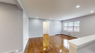 This single-floor residence showcases a clean, modern aesthetic with a well-considered layout across its living areas. The open living space immediately impresses with richly polished hardwood floors that reflect natural light pouring in through multiple windows. Soft gray walls throughout create a calm, neutral backdrop, while recessed lighting adds a refined, contemporary touch.

The kitchen is a standout feature, outfitted with dark charcoal cabinetry, light stone countertops, and a classic subway tile backsplash. Stainless steel appliances — including a gas range, built-in microwave, and dishwasher — complete the modern culinary space, complemented by light wood-toned tile flooring and a window that brings in natural light.

The bedrooms continue the cohesive design language with the same gleaming hardwood floors, neutral gray walls, and ample natural light from well-positioned windows. One bedroom features a built-in closet with double doors, offering practical storage. Baseboard heating is present throughout, ensuring year-round comfort.

The bathroom is elegantly appointed with large-format marble-style wall tiles surrounding a full soaking tub, a built-in niche for storage, and a frosted privacy window. The space conveys a spa-like quality with its crisp white tones and refined tile work. Overall, this residence offers a polished, move-in-ready environment with consistent, high-quality finishes throughout.