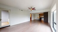 Located at 2144 E Republic Rd in Springfield, MO, this single-floor unit presents a clean, contemporary design throughout. The open-concept living and dining area is anchored by light-toned hardwood-style flooring and a ceiling fan, creating a bright, airy atmosphere. Large black-framed windows invite natural light and offer pleasant outdoor views of surrounding greenery, enhancing the sense of openness.

The kitchen is positioned adjacent to the living area and features a stainless steel electric range with a sleek hood vent, dark countertops, a combination of light upper cabinets and dark wood-grain lower cabinetry, and a stainless steel refrigerator. A butcher-block island provides additional workspace and visual contrast.

The bedrooms are carpeted for comfort, each equipped with ceiling fans and generous closet space, including sliding wood-panel closet doors. Several bedrooms feature large windows with outdoor views, contributing to a well-lit environment.

The bathroom is finished with neutral tile surrounding the tub-shower combination, a dark wood-grain floating vanity, a dark countertop with an undermount sink, chrome fixtures, and a large wall mirror, delivering a cohesive and modern aesthetic throughout.