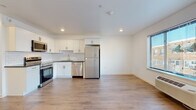 Located at 404 Fountain St in Philadelphia's Roxborough neighborhood, this single-floor unit at The Wright presents a clean, modern aesthetic with thoughtfully selected finishes. The open-plan living and kitchen area is anchored by light-toned hardwood-style flooring that runs throughout, creating a seamless and cohesive feel across the space.

The kitchen is well-appointed with crisp white shaker cabinetry, dark countertops, and a classic white subway tile backsplash. A full suite of stainless steel appliances includes a refrigerator, range with oven, over-the-range microwave, and dishwasher. Recessed lighting illuminates the kitchen and living area, while a large window allows natural light to flow in and provides neighborhood views.

The living area offers generous open space, with a wall-mounted HVAC unit ensuring year-round comfort. The bedroom is a bright, well-proportioned room with its own window and continued hardwood-style flooring. The bathroom features a soaking tub and shower combination framed by striking large-format marble-look tile, adding an elevated touch to the overall design. Clean white walls and recessed lighting are consistent throughout, giving the unit a bright, move-in-ready feel.