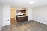 This single-floor unit offers a thoughtfully designed layout that maximizes functionality across its key living spaces. The main living area features dark hardwood-style flooring, neutral gray walls, and a textured ceiling, creating a warm yet contemporary atmosphere. A wall-mounted air conditioning unit and a large window with blinds allow for natural light and climate control, while a smart lock on the entry door adds a modern security touch.

The kitchen is equipped with stainless steel appliances, including a refrigerator, electric range, and over-the-range microwave. Dark cabinetry with a subway tile backsplash complements the granite-style countertops, and a peninsula with a built-in sink and track lighting overhead adds both style and practicality. The open-concept design allows the kitchen to flow seamlessly into the living space.

The bathroom is a standout feature, showcasing a vessel sink atop a dark vanity with granite countertops, framed mirrors, and contemporary lighting fixtures. Dark wood-style flooring continues from the main area, and a separate water closet with a bathtub-shower combination provides added privacy. A walk-in closet adjacent to the bathroom offers generous storage space with a dedicated rod and shelving system.