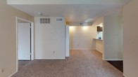 This single-floor unit is thoughtfully laid out to maximize functionality across its living spaces. The living room serves as the central gathering area, highlighted by a wood-paneled fireplace and a window that allows natural light to fill the room. Plush wall-to-wall carpeting runs throughout the living and bedroom areas, adding warmth and comfort underfoot. A textured popcorn ceiling is consistent throughout the unit, lending a classic residential character to each room.

The kitchen is designed in a galley configuration, featuring dark cabinetry that contrasts with light granite-style countertops. White appliances, including a coil-burner range and refrigerator, are provided, and durable wood-look flooring lines the kitchen floor. A pass-through counter connects the kitchen to the adjacent living or dining area, enhancing the sense of openness.

The bedrooms are comfortably sized, each equipped with blinds-covered windows that provide privacy while allowing adjustable natural light. The bathroom includes a vanity with dark cabinetry and granite-style countertops, a large mirror with overhead lighting, and a full tub-shower combination with tiled surround. Overall, the unit presents a clean, functional living environment with a neutral color palette throughout.