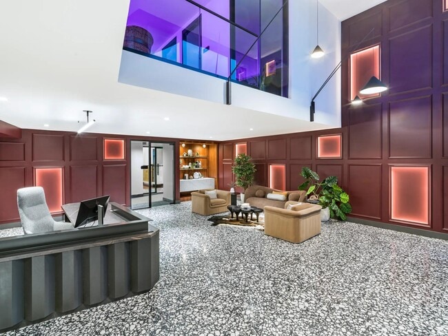 A bold lobby design welcomes you with layered textures, colorful lighting, and plush lounge seating. - Modera SoBro