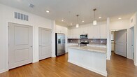 Located at 13600 Hilltop Groves Blvd in Clermont, FL, this well-designed one-bedroom, one-bathroom residence offers a thoughtful layout across a single floor. The open-concept living and kitchen area is anchored by a stylish kitchen featuring crisp white cabinetry, granite countertops, a grey subway tile backsplash, and a full suite of stainless steel appliances including a French door refrigerator, electric range, and microwave. Pendant lighting above the kitchen peninsula adds a modern touch, while recessed lighting and warm wood-look flooring carry throughout the main living areas. The bedroom is a comfortable, well-lit retreat with plush carpeting, a ceiling fan, and multiple windows fitted with blinds that invite natural light and outdoor views. The bathroom is cleanly appointed with wood-look flooring, a granite-topped vanity, white cabinetry, and a tiled tub-shower combination. A dedicated in-unit laundry area houses a stacked washer and dryer, adding everyday convenience. Clean white walls, consistent finishes, and a bright, airy atmosphere give this residence a cohesive and move-in-ready character throughout.
