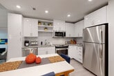 Unit 413 at 1111 New Jersey Avenue SE offers a thoughtfully designed one-bedroom, one-bathroom residence in Washington, DC's Capitol Riverfront neighborhood. Light-toned hardwood-style flooring flows throughout the open-concept main living area, unifying the kitchen, dining, and living spaces into a cohesive and functional layout.

The modern kitchen is appointed with high-gloss white cabinetry, granite countertops, a white subway tile backsplash, and a full suite of stainless steel appliances, including a gas range, built-in microwave, dishwasher, and refrigerator. Open shelving adds both storage and display space. The adjacent dining area accommodates a full dining table, while the living room benefits from a large floor-to-ceiling window that draws in natural light and provides views of the surrounding neighborhood.

The bedroom is a calm, well-proportioned retreat with neutral walls and dedicated closet storage. The bathroom features classic white subway tile surrounding a full soaking tub and shower combination, complemented by a granite-topped vanity and tile flooring. A dedicated laundry area adds everyday convenience. Recessed lighting throughout the unit provides consistent, clean illumination, contributing to the overall bright and contemporary ambiance of the space.