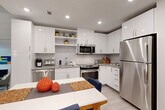 Unit 413 at 1111 New Jersey Avenue SE offers a thoughtfully designed one-bedroom, one-bathroom residence in Washington, DC's Capitol Riverfront neighborhood. Light-toned hardwood-style flooring flows throughout the open-concept main living area, unifying the kitchen, dining, and living spaces into a cohesive and functional layout.

The modern kitchen is appointed with high-gloss white cabinetry, granite countertops, a white subway tile backsplash, and a full suite of stainless steel appliances, including a gas range, built-in microwave, dishwasher, and refrigerator. Open shelving adds both storage and display space. The adjacent dining area accommodates a full dining table, while the living room benefits from a large floor-to-ceiling window that draws in natural light and provides views of the surrounding neighborhood.

The bedroom is a calm, well-proportioned retreat with neutral walls and dedicated closet storage. The bathroom features classic white subway tile surrounding a full soaking tub and shower combination, complemented by a granite-topped vanity and tile flooring. A dedicated laundry area adds everyday convenience. Recessed lighting throughout the unit provides consistent, clean illumination, contributing to the overall bright and contemporary ambiance of the space.