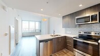 Located at 1475 Island Ave in San Diego's vibrant East Village neighborhood, this contemporary single-floor residence combines modern design with striking urban views. The open-concept layout seamlessly connects the kitchen and living area, creating a bright and functional living space bathed in natural light from floor-to-ceiling windows.

The kitchen is a standout feature, outfitted with dark wood-grain cabinetry, white quartz countertops, a subway tile backsplash, and a full suite of stainless steel appliances including a refrigerator, range, built-in microwave, and dishwasher. A peninsula with a double undermount sink provides additional prep space and serves as a natural divider between the kitchen and living area.

The living area is anchored by expansive windows that frame impressive views of the San Diego skyline, neighboring high-rises, and the iconic Coronado Bridge. Wood-style plank flooring runs throughout the space, adding warmth to the clean, neutral palette.

The bedroom offers generous proportions with the same sweeping city views and continuity of flooring. The bathroom features a white quartz vanity with an undermount sink, chrome fixtures, a large mirror, recessed lighting, and a marble-tiled shower surround. The overall aesthetic is polished, minimal, and move-in ready.