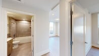 Located at 3220 Prospect St NW in Washington, DC's prestigious Georgetown neighborhood, this thoughtfully designed one-bedroom, one-bathroom residence offers a clean, modern aesthetic throughout. Light hardwood flooring runs seamlessly across the living area, kitchen, hallway, and bedroom, creating a cohesive and airy feel.

The open living and kitchen area is efficiently laid out, featuring light wood cabinetry, a tile backsplash, and a full suite of stainless steel appliances including a refrigerator, range, built-in microwave, and dishwasher. A pair of large double-hung windows floods the space with natural light and frames views of the surrounding Georgetown rooftops and a green roof below.

The bedroom is a quiet retreat with its own set of large windows equipped with roller shades, continuing the views of the neighborhood skyline. The room comfortably accommodates essential furnishings and is finished with the same warm hardwood flooring.

The bathroom is well-appointed with large-format, neutral-toned tiles lining the walls of a full soaking tub and shower combination, complemented by a built-in niche shelf and chrome fixtures. A hallway connects all rooms with ease, completing this compact yet functional layout ideal for urban living in one of DC's most sought-after neighborhoods.