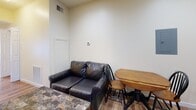 Located at 1067 Philadelphia St in Indiana, Pennsylvania, this single-floor unit offers a practical and straightforward layout designed for comfortable everyday living. The space flows from the open kitchen and living area through to a private bedroom and bathroom.

The kitchen is well-equipped with warm medium-toned wood cabinetry, granite-style countertops, and a full suite of black appliances, including a refrigerator, electric range, built-in microwave, and dishwasher. Recessed lighting illuminates the space, and hardwood-style flooring extends throughout, lending a cohesive feel to the interior.

Adjacent to the kitchen, the living and dining area provides room for seating and a small dining table. The space features neutral cream-toned walls and visible ceiling ventilation, keeping the environment comfortable year-round.

The bedroom is a compact, private room with the same hardwood-style flooring and clean, light-colored walls. It offers a quiet retreat with enough space for a bed and a small desk or chair.

The bathroom includes a full-size tub and shower combination with chrome fixtures and a safety grab bar, finished in clean white tones. Overall, the unit presents a no-frills, functional living environment suited for individuals or small households.