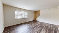 This two-story home offers a well-organized layout across two floors, providing comfortable living space for everyday life. The main floor features a bright and open living room finished with wide-plank hardwood-style flooring and a large bay window that fills the room with natural light. A staircase with a railing connects the main level to the upper floor. The kitchen is equipped with warm honey-toned cabinetry, granite-style countertops, a peninsula for additional prep and seating space, and stainless steel appliances including a refrigerator, range, and microwave. Two full bathrooms serve the home, one of which includes a soaking tub with stone-look tile surround, and the other finished in a clean, neutral palette. Upstairs, three bedrooms provide restful retreats, each carpeted in neutral tones and featuring windows that invite natural light. The generously sized primary bedroom offers a comfortable and private space. Additional bedrooms are well-proportioned and include closet storage with built-in hanging rods. Two hallways connect the spaces across both levels, while two dedicated closets offer practical storage solutions throughout the home. The overall design is clean, functional, and move-in ready.