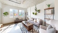 Located in the vibrant RiNo neighborhood of Denver, this urban loft-style residence at 2101 Market St showcases an industrial-chic aesthetic defined by exposed concrete ceilings, visible ductwork, and warm wood-tone flooring throughout. The open-concept layout creates a seamless flow between the living, dining, and kitchen areas, maximizing the sense of space and light.

The gourmet kitchen is a standout feature, outfitted with rich dark-wood cabinetry, granite countertops, a white subway tile backsplash, and a full suite of stainless steel appliances including a gas range, dishwasher, microwave, and refrigerator. A peninsula with a granite overhang and bar seating provides a casual dining option and doubles as a workspace.

The living area is bathed in natural light from large windows that frame views of Denver's colorful street murals and skyline. The exposed concrete ceiling and open plan give the space an airy, loft-like quality that is both functional and visually striking.

The bedroom continues the industrial aesthetic with exposed ceiling elements, expansive windows offering city views, and plush carpeting for comfort. The bathroom features wood-look flooring, a granite-topped dark wood vanity, and a full tub-shower combination, maintaining the consistent design language found throughout the residence.